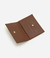 Billetera pequeña tipo sobre color marrón, confeccionada en cuero sintético. Presenta apliques decorativos metálicos en forma de estrellas y círculos en la parte frontal.