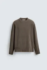 Jersey de punto con textura, corte relajado, cuello redondo y manga larga con acabados en rib.