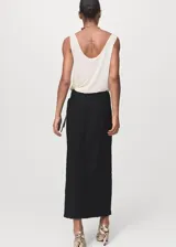 Falda midi tiro medio de color negro, con diseño cruzado y tajo delantero.