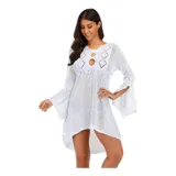 Vestido de playa corto en tejido calado color crema, con mangas largas acampanadas y diseño asimétrico con volado en el ruedo. Presenta un escote redondo con abertura frontal y cordón ajustable.
