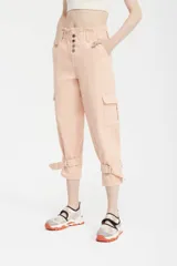 Pantalón capri color melocotón, de tiro alto con cintura elastizada y cuatro botones, bolsillos cargo laterales con solapa y ajuste con hebilla en los tobillos.