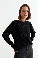 Sweater de manga larga, color negro, con cuello redondo y estampado de pequeños corazones dorados distribuidos por toda la prenda.