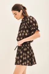 Short de voile de algodón con estampado floral en tonos beige sobre fondo negro. Presenta un diseño de corte amplio con cintura elástica y lazo ajustable para un calce cómodo.