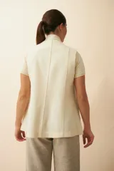 Chaleco color crema con solapas, corte entallado y bolsillos plaqué.