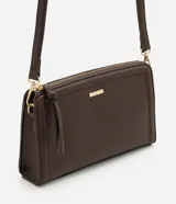 Cartera transversal Satinato de tamaño pequeño, color marrón, confeccionada en PU con cierre de cremallera y herrajes dorados. Incluye correa larga ajustable y detalle de tira colgante en el cierre.