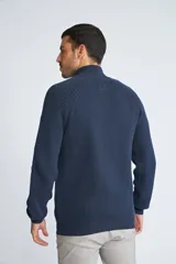 Campera tejida de algodón con cierre frontal completo, cuello alto y mangas largas con puños acanalados. Presenta un diseño de punto acanalado vertical y un pequeño logo bordado en el ruedo.