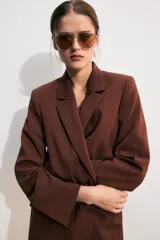 Blazer marrón de cuello solapa con muescas, manga larga y bolsillos de vivo con solapa. Cierre frontal con un botón.