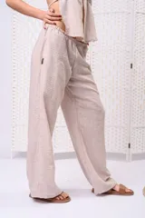 Pantalón palazzo de lino color beige, de tiro medio-alto, con cintura elastizada y silueta holgada de caída fluida.