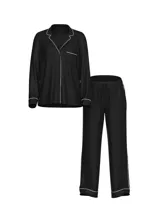 Pijama largo de satín negro, compuesto por una camisa de manga larga con botones, cuello con muesca, bolsillo en el pecho y ribete blanco, y un pantalón largo a juego con cintura elástica.
