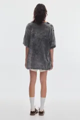Remera boxy de manga corta y cuello redondo, con efecto de lavado acid wash en tono gris y estampa frontal en tonos rosado y rojo.