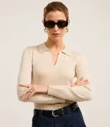 Blusa de punto ajustada color negro, con cuello polo y escote pronunciado en V. Presenta un tejido acanalado vertical en el torso y mangas largas.