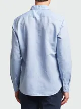 Camisa de manga larga para hombre, color celeste claro, con cuello clásico y botones frontales. El interior del puño presenta un estampado geométrico en contraste en color negro y blanco.