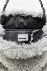 Cartera de hombro gris con textura peluda y correa larga ajustable.