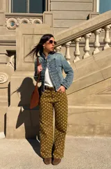 Chaqueta de denim estilo militar, de corte corto, cuello mao y múltiples hileras de botones metálicos frontales.