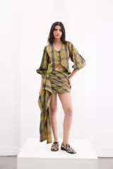 Minifalda semi entallada de tafeta con estampa a cuadros en tonos verde militar y gris oscuro, con diseño cruzado y un lazo largo lateral.
