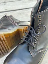 Bota corta de cuero color chocolate, con cordones amarillos y cierre lateral.