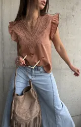 Musculosa de algodón color terracota, con escote en V y cuello ribeteado con bordados en relieve. Presenta mangas cortas con volados sutiles y diseño recto.