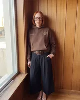 Canguro oversize color marrón con capucha y bolsillo frontal. Presenta un estampado gráfico circular en la espalda con tipografía estilizada en color crema.