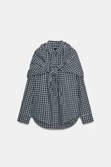Camisa oversize de algodón con estampado de cuadros, cuello solapa, manga larga con puños y cierre frontal con botones. Presenta un detalle de pañuelo integrado en el mismo tejido que se anuda en la parte frontal.
