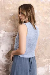 Chaleco corto tejido a mano en crochet, color celeste, con silueta ajustada, sin mangas y lazos en la delantera.