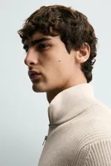 Jersey de punto perlado con cuello perkins y cierre frontal de cremallera. Presenta un corte regular fit, manga larga y acabados en rib en puños y bajo.