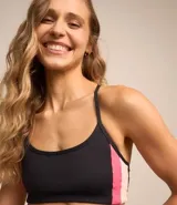 Top deportivo negro con recortes laterales en rosa y blanco, breteles finos y sin copa.