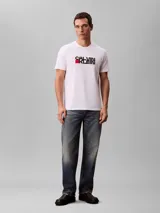 Remera Calvin Klein de color blanco, de corte regular y manga corta, con cuello redondo. Cuenta con un estampado gráfico artístico de la marca en el pecho en tonos negros y detalles en rojo.