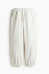 Pantalón deportivo de felpa color blanco roto, con interior cepillado suave. Presenta elástico revestido y cordón ajustable en la cintura, bolsillos laterales y puños acanalados. Corte relajado.