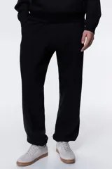 Pantalón deportivo negro de felpa con interior cepillado suave. Modelo de corte relajado con elástico revestido y cordón ajustable en la cintura, bolsillos laterales y puños acanalados.