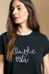 Remera de manga corta color marrón, con la frase "la dolce vita" bordada en azul en el frente y mangas con dobladillo.