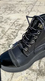 Borcegos de cuero tostado con plataforma bicolor, puntera y talón negros, detalles en animal print y cordones oscuros.