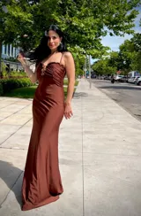 Vestido largo de fiesta color marrón chocolate, con breteles finos, escote fruncido y detalle de adorno metálico en el centro.