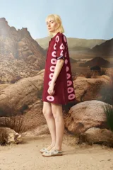 Vestido corto de tejido jacquard en color bordó con estampado de estrellas rosadas en los laterales. Presenta cuello polo con cierre frontal de botones y mangas cortas con terminación en contraste.