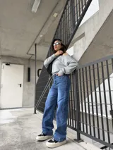 Pantalón de jean azul con corte recto y tiro alto, presenta detalles de tachas metálicas en los bolsillos delanteros.