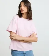Remera de algodón color rosa claro, con corte oversized, cuello redondo y mangas cortas amplias con el bajo doblado.