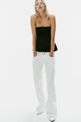 Top negro de tejido satinado, sin tirantes y con escote recto. Presenta costuras marcadas y diseño con peplum en la parte inferior, con cierre de cremallera oculta en la espalda.