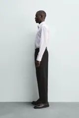 Camisa de corte regular fit con cuello italiano y manga larga con puños abotonados. Presenta un diseño de rayas verticales finas en tono suave sobre fondo claro, con cierre frontal de botones.