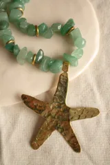 Collar con cuentas de piedra verde y dije de estrella de mar de bronce.