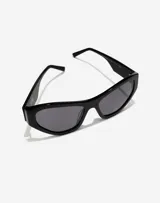 Lentes de sol Hawkers x Tini modelo Code, con armazón de acetato negro y diseño cat-eye. Presentan cristales oscuros y detalles de marca grabados en las patillas.