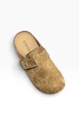Zueco de gamuza color marrón camel, con diseño cerrado en la parte delantera y tira ajustable con hebilla metálica en el empeine.
