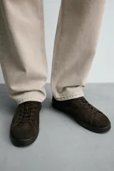 Zapatilla de cordones confeccionada en piel con acabado de serraje, de horma redonda y suela a tono.