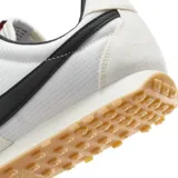 Championes Nike modelo Pre Montreal Racer Vintage, con diseño retro de perfil bajo. Presenta una base de tela técnica blanca con refuerzos de gamuza en tono gris claro en la puntera y el talón. Incluye el logo de Nike en color negro en los laterales y suela de goma con relieve para mayor tracción.