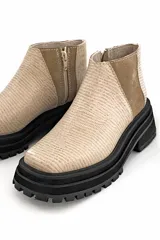 Botín color beige con textura acanalada, paneles laterales de gamuza color camel y suela track color negro.