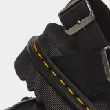 Sandalias Dr. Martens modelo Voss II, color negro, con tiras cruzadas en el empeine, correas ajustables con hebilla en el talón y tobillo, suela flatform dentada de EVA con el inconfundible pespunte amarillo de la marca.