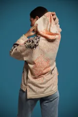 Buzo oversize de corte amplio con capucha, cordón de ajuste y aberturas en los costados del ruedo. Presenta una estampa multicolor con motivos de animales y flores.