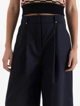 Pantalon de vestir azul marino con corte wide leg, tiro alto y pinzas frontales que aportan volumen. Cuenta con cierre frontal, doble gancho de ajuste y presillas con detalles de remaches metálicos.