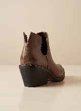 Botín de cuero vacuno color negro, con diseño de corte lateral y taco cuadrado de 5 cm. Presenta punta fina y suela de caucho antideslizante.