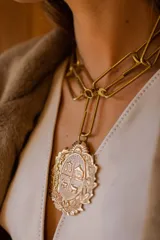 Collar dorado con cadena de eslabones grandes y dije con forma de escudo heráldico.