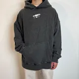 Canguro con capucha de corte oversize y efecto lavado, color gris oscuro. Presenta un estampado pequeño en el pecho con el dibujo de un auto y la inscripción 'EST. VCP 2015'. Cuenta con bolsillo frontal tipo canguro y etiqueta pequeña en el puño.