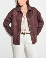 Sobrecamisa de gamuza sintética en color marrón chocolate, con corte oversize, cuello camisero, cierre frontal con botones y bolsillos frontales tipo parche.